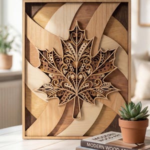 Puede incluir: Arte de pared de madera con un diseño de hoja de arce en capas. La hoja está intrincadamente cortada con patrones decorativos y colocada sobre un fondo de paneles de madera curvados en varias tonalidades de marrón y beige.