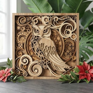 May include: A wooden, multi-layered owl art piece. The owl is intricately cut from light-colored wood, with detailed feathers and facial features. The artwork is framed in a square wooden frame, with decorative swirls and gears surrounding the owl. Red flowers and green leaves are in the foreground.