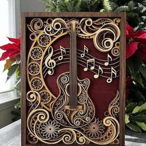 May include: A layered wooden artwork depicting a guitar and musical notes. The piece is framed in dark brown wood with a red backdrop. The design incorporates intricate floral and gear-like patterns in light brown and tan, creating a detailed effect.