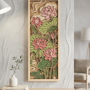 Pode incluir: Uma peça de arte de parede retangular em madeira com um design multicamadas cortado a laser de flores de lótus cor-de-rosa e folhas de nenúfar verdes. A obra está emoldurada em madeira clara e exibe uma cena botânica tridimensional.