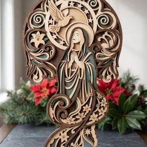 May include: Wooden layered art piece depicting a religious figure with hands clasped in prayer. The artwork features a dove, stars, and floral elements in shades of brown, beige, and teal. The piece is likely a decorative item.