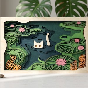 Pode incluir: Uma peça de arte de parede em madeira multicamadas com uma cena de lago com a cabeça e a cauda de um gato branco emergindo de água azul-escura. O design inclui vitórias-régias verdes, flores de lótus cor-de-rosa e estruturas cor de laranja.