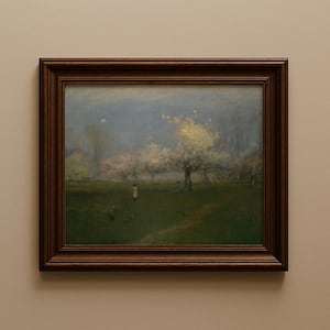 May include: A framed landscape painting depicting a serene outdoor scene. The artwork features a green field, blossoming trees, and a figure in the distance. The frame is a dark brown color.