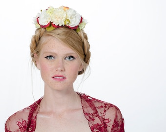 May include: A woman with freckles and blonde hair wearing a red lace shawl and a white flower crown.