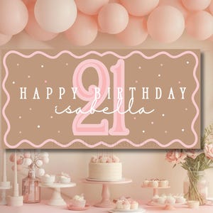 Puede incluir: Una pancarta marr&oacute;n con el texto "HAPPY BIRTHDAY isabella" y el n&uacute;mero "21" en rosa. La pancarta tiene un borde rosa ondulado y lunares blancos. La escena incluye globos y una tarta, creando un ambiente festivo.