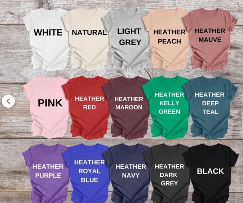 K&ouml;nnte beinhalten: Eine Sammlung von f&uuml;nfzehn kurz&auml;rmeligen T-Shirts mit Rundhalsausschnitt, angeordnet in drei Reihen, jeweils beschriftet mit der Farbe: White, Natural, Light Grey, Heather Peach, Heather Mauve, Pink, Heather Red, Heather Maroon, Heather Kelly Green, Heather Deep Teal, Heather Purple, Heather Royal Blue, Heather Navy, Heather Dark Grey und Black.