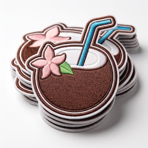 May include: A stack of embroidered patches, each shaped like a brown coconut drink with a white interior, a bright blue straw, and a light pink tropical flower with a small green leaf attached to the side, featuring detailed stitching throughout.