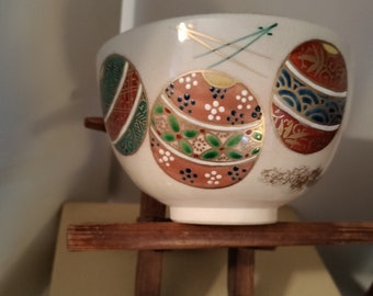 Vintage Japanese hand-made Kyoware glazed tea bowl, chawan . Painted on-glaze enamel temari balls and pine needles.  White porcelain body.