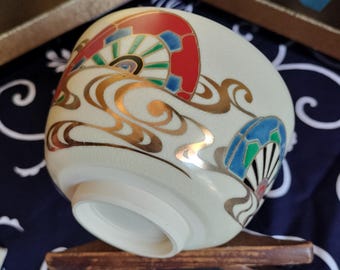 Vintage Japanese hand-made tea bowl. Kyo-ware, white stoneware, with cream glaze and on-glaze design of Genjiguruma wheels in water. Artist