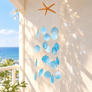 May include: A hanging mobile featuring a natural tan starfish at the top, with multiple translucent, circular blue shell discs suspended by thin white strings. Small wooden beads are placed above each shell disc to secure them in place.