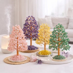 Puede incluir: Cuatro árboles decorativos de cristal en rosa, morado, amarillo y verde. Cada árbol tiene un tronco color cobre y una base de cristales a juego. Los árboles están dispuestos sobre una superficie blanca con un difusor y cristales adicionales.