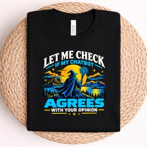 Może przedstawiać: Czarny t-shirt z grafiką przedstawiającą czarodzieja trzymającego świecącą laskę na tle dużego żółtego księżyca. Napis głosi: LET ME CHECK IF MY CHATBOT AGREES WITH YOUR OPINION. Wzór zawiera niebieskie góry, jezioro i drzewa.