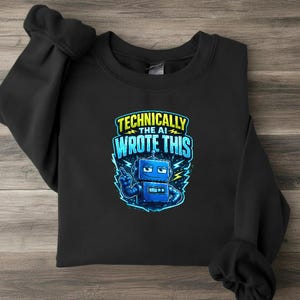Könnte beinhalten: Ein schwarzes Langarm-Sweatshirt mit einer Grafik eines blauen Roboters mit selbstgefälligem Ausdruck, der nach oben zeigt. Der Text über dem Roboter lautet "TECHNICALLY THE AI WROTE THIS" in gelben und hellblauen Buchstaben auf dunklem Grund.