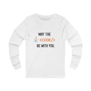 May include: White long-sleeve shirt with the text "MAY THE CODE BE WITH YOU." The design includes a coffee cup, angled brackets, and a flame icon. The shirt is a casual wear item.