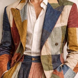 May include: A patchwork blazer and matching trousers in a variety of colors including blue, red, yellow, and beige. The blazer has a double-breasted design with two buttons. The outfit is paired with a white button-down shirt.