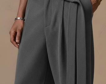 May include: Charcoal gray pleated trousers with a matching belt. The pants have a textured, ribbed fabric and a button closure. The belt wraps around the waist and fastens with a button. The trousers have a relaxed fit and a classic design.