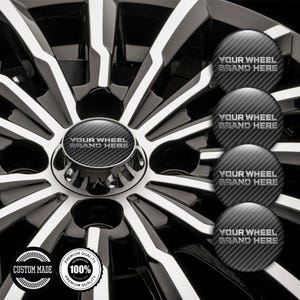 May include: A close-up of a car wheel with a black and silver spoke design. The center cap and additional caps feature a carbon fiber pattern and the text "YOUR WHEEL BRAND HERE". Two circular stickers read "CUSTOM MADE" and "100% PREMIUM QUALITY".