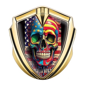 May include: A gold-colored shield-shaped emblem featuring a colorful skull design. The skull is split, with one side displaying the American flag and the other side with red and yellow stripes. The skull has green eyes and dripping paint.