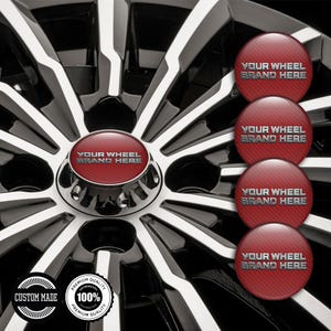 May include: A car wheel with a black and silver spoke design. The centre cap is red with the text "YOUR WHEEL BRAND HERE". Additional red caps with the same text are displayed. The image also includes two circular badges that read "CUSTOM MADE" and "PREMIUM QUALITY 100% PREMIUM QUALITY".