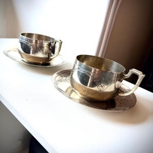 Op de afbeelding: Een witte keramische mok met een zwart handvat en de tekst "But First, Coffee" in een zwarte, vette letter. De mok staat op een wit oppervlak.