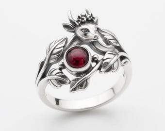 Anello in argento con testa di cervo, pietra cabochon rossa e fascia a motivo di foglie e viticci.