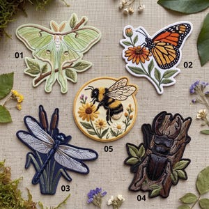May include: Five embroidered patches featuring insects and nature motifs: 01 a pale green luna moth on a branch, 02 an orange monarch butterfly on a flower, 03 a blue dragonfly with cattails, 04 a dark beetle on bark, and 05 a bumblebee on flowers.