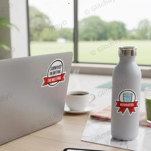Op de afbeelding: Een laptop met een sticker met de tekst "Survived the Meeting" staat naast een grijze waterfles met een "Hydrated" sticker. Een kopje koffie en een glas groen sap staan ook op tafel. Iemand werkt op de laptop.