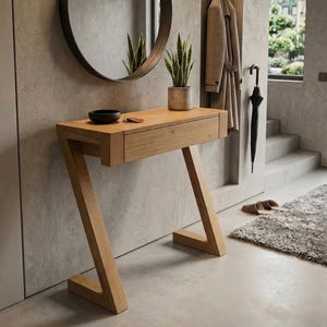 May include: A light brown wooden console table with a Z-shaped base and a single horizontal drawer. The tabletop holds a small black bowl, a set of keys, and a potted green plant. The furniture features a natural wood grain finish throughout.