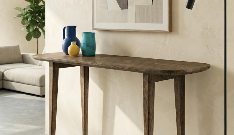 K&ouml;nnte beinhalten: Ein dunkelbrauner Holzkonsolentisch mit einer glatten, l&auml;nglichen Platte und vier konisch zulaufenden Beinen. Drei Keramikvasen in Blau, Gelb und T&uuml;rkis stehen auf der Oberfl&auml;che. Der Tisch hat ein schlichtes Design mit sichtbarer Holzmaserung.
