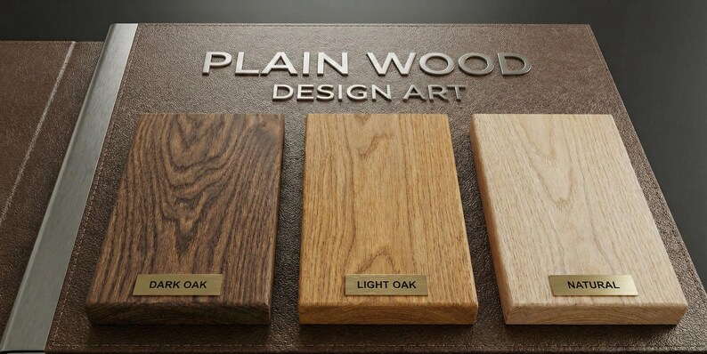 May include: A display board titled PLAIN WOOD DESIGN ART featuring three rectangular wood samples. The samples are labeled with small metal plates reading DARK OAK, LIGHT OAK, and NATURAL, showcasing distinct wood grain patterns and color tones.