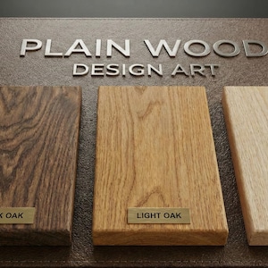 K&ouml;nnte beinhalten: Ein Pr&auml;sentationsboard mit der Aufschrift PLAIN WOOD DESIGN ART und drei rechteckigen Holzmustern. Die Muster sind mit kleinen Metallschildern versehen, die DARK OAK, LIGHT OAK und NATURAL beschriftet sind und verschiedene Holzmaserungen zeigen.