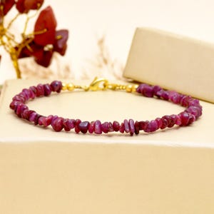 Peut inclure: Un bracelet composé d'éclats de rubis rouge foncé avec un fermoir doré. Le bracelet est composé de petites pierres de rubis de forme irrégulière. Le fermoir et les perles de connexion sont dorés.