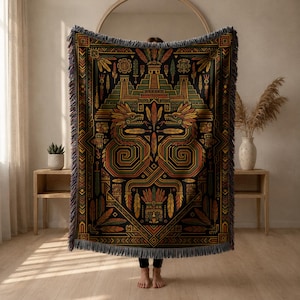 Peut inclure: Un plaid tissé rectangulaire présentant un fond sombre avec un motif symétrique et complexe dans des tons de vert, orange et jaune. Le design comprend des structures pyramidales stylisées, des motifs de serpents à plumes et des bordures géométriques à franges.