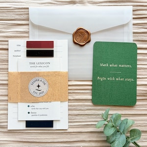 May include: A stationery set featuring a white envelope sealed with a gold wax stamp. The set includes a card with the text "Mark what matters. Begin with what stays." and a notepad with the text "THE LEXICON words for what you felt."