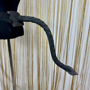 Puede incluir: Accesorio de disfraz de cola de drag&oacute;n negro, con una fijaci&oacute;n de cintur&oacute;n y una cola curvada. La cola est&aacute; detallada con patrones de escamas y est&aacute; hecha de un material oscuro. Ideal para cosplay.