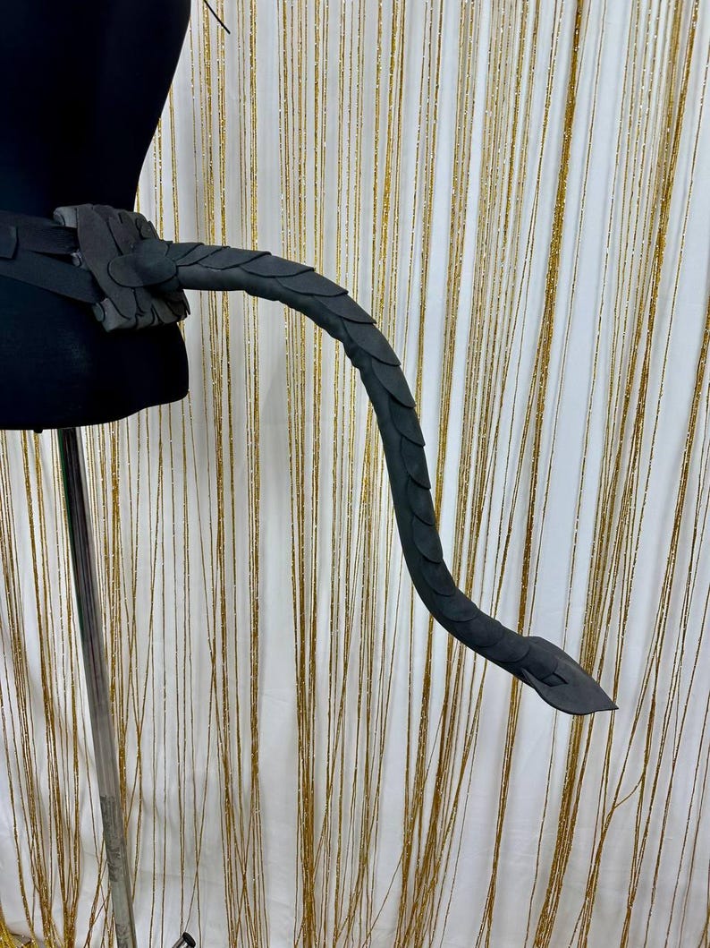 Puede incluir: Accesorio de disfraz de cola de drag&oacute;n negro, con una fijaci&oacute;n de cintur&oacute;n y una cola curvada. La cola est&aacute; detallada con patrones de escamas y est&aacute; hecha de un material oscuro. Ideal para cosplay.