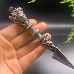 May include: An intricately designed silver dagger. The handle features a detailed dragon motif, and the blade is pointed. The dagger's design suggests a ceremonial or decorative function, with elaborate carvings and detailing throughout.