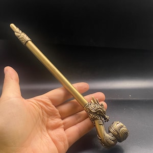 May include: A brass pipe with a dragon head design. The pipe has a long, slender stem and a curved bowl. The dragon head is intricately detailed, and the pipe has a vintage look.