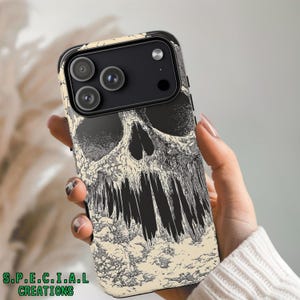 May include: Black and cream-colored phone case featuring a detailed skull design. The case has a black border and a textured appearance. The text "S.P.E.C.I.A.L CREATIONS" is printed at the bottom in green.
