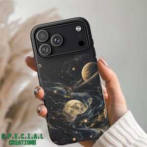 Könnte beinhalten: Schwarze Handyhülle mit einem Weltraum-Design, das Planeten, Sterne und wirbelnde Nebel in Gold, Blau und Schwarz zeigt. Die Hülle hat ein schwarzes Kameramodul und den Text "S.P.E.C.I.A.L CREATIONS" in Grün.