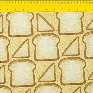 May include: Fabric with a repeating pattern of bread slices and triangles. The bread has a light tan crust and a white interior. The background is a light yellow with a subtle swirl design. The pattern is suitable for kitchen or food-themed projects.