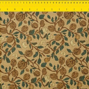 May include: A repeating pattern featuring walnuts, leaves, and cashews on a tan backdrop. The walnuts are brown, the leaves are dark green, and the cashews are off-white. The branches are a dark brown colour. Suitable for fabric or wallpaper.