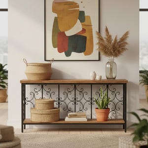 May include: A decorative console table with a wooden top and black metal scrollwork. The table holds woven baskets, books, and a potted plant. A framed abstract art piece hangs above the table, and a vase with dried flowers sits on the table.