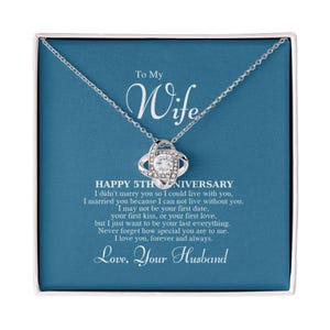 Könnte beinhalten: Eine silberne Halskette mit einem funkelnden Anhänger in einer Geschenkbox. Der Anhänger ist ein Knoten-Design mit einem zentralen Cluster aus klaren Kristallen. Die Box hat einen blauen Hintergrund mit dem Text "To My Wife" und eine Botschaft zum 5. Jahrestag.