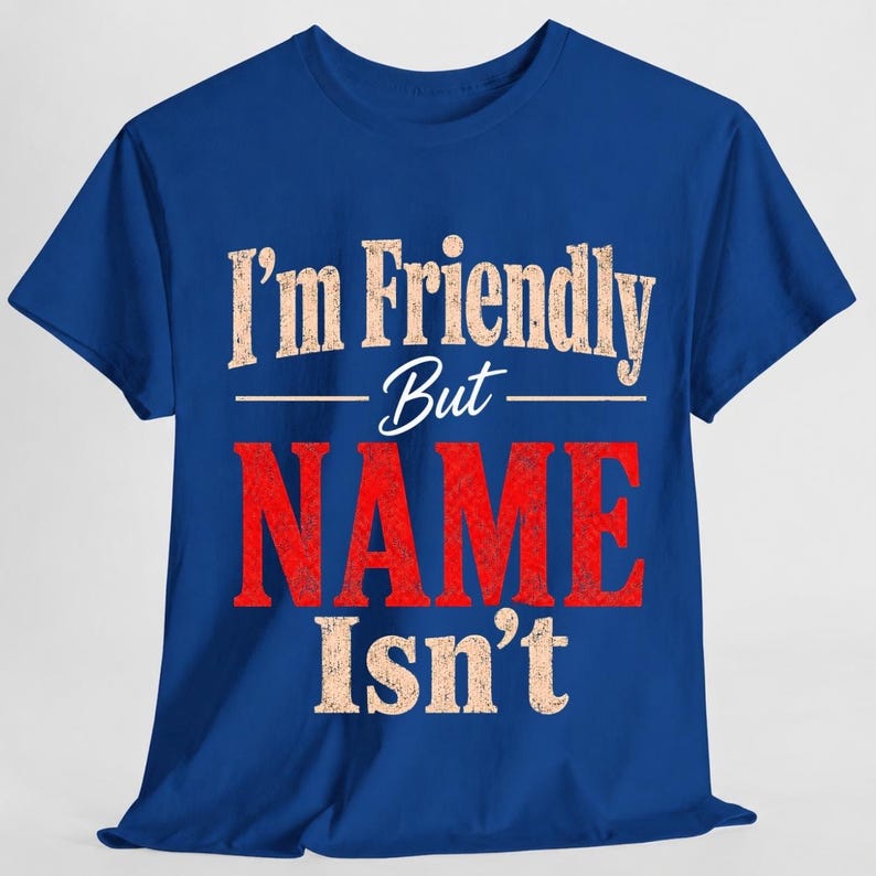 May include: A royal blue short-sleeve t-shirt featuring the text "I'm Friendly But NAME Isn't" printed on the front. The words "I'm Friendly" and "Isn't" are in a distressed beige font, while the word "NAME" is in a large, bold, distressed red font.