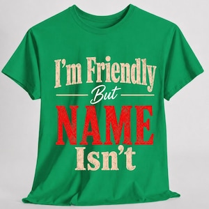May include: A bright green short-sleeved t-shirt featuring the text "I'm Friendly But NAME Isn't" printed on the front. The words "I'm Friendly But" and "Isn't" are in a distressed beige font, while the word "NAME" is in a large, bold red font.