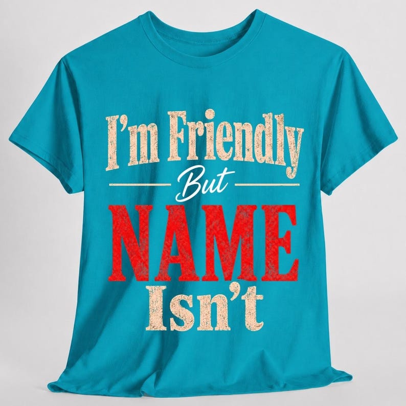 May include: A bright turquoise short-sleeve t-shirt featuring the text "I'm Friendly But NAME Isn't" printed on the front. The words "I'm Friendly But" and "Isn't" are in a distressed beige font, while the word "NAME" is in large red letters.