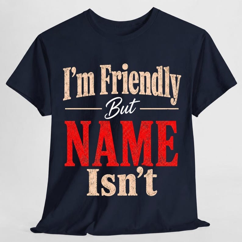 May include: A dark navy blue short-sleeve t-shirt featuring the text "I'm Friendly But NAME Isn't" printed on the front. The words "I'm Friendly But" and "Isn't" are in a distressed beige font, while the word "NAME" is in large red letters.