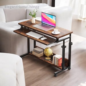 May include: A brown and black adjustable laptop desk with a keyboard tray, lower shelf, and wheels. A laptop, keyboard, mouse, and coffee cup are on the desk. A globe, books, and decorative boxes are on the shelf. The text "ElegantHomeLivingg" is in the top left corner.