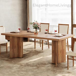 May include: A large, rectangular wooden dining table with a natural finish. The table is set with white plates, wine glasses, and a floral centerpiece. The table is supported by thick, vertical wooden legs. The text "ElegantHomeLivingg" is visible.